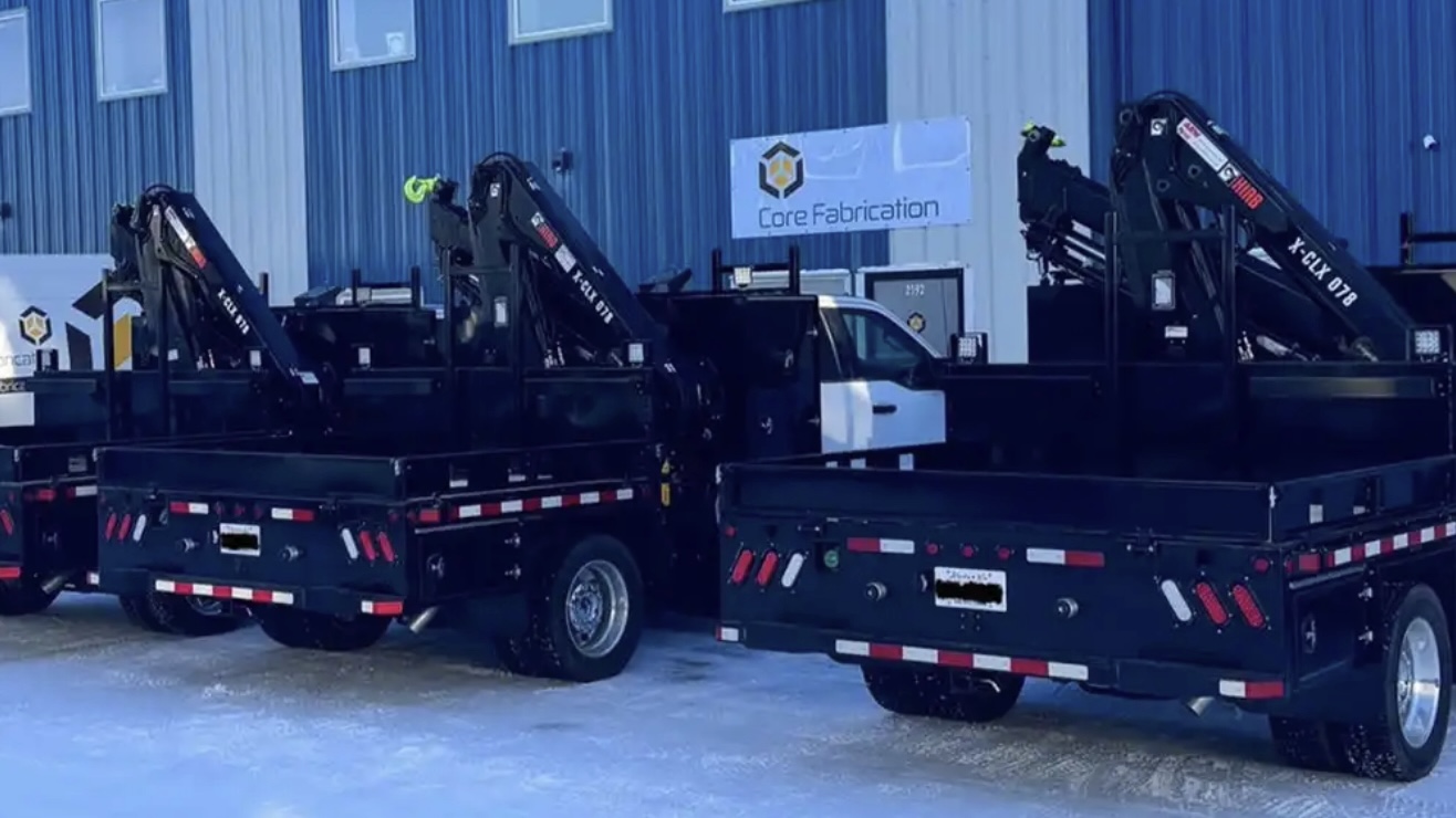 Fleet of picker trucks parked outside Core Fabrication facility in Alberta